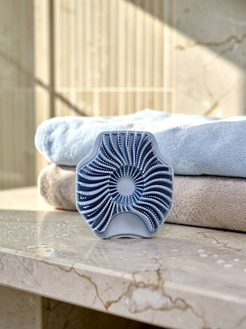 Norevella BodySilk compact silicone body scrubber in a premium shower setting